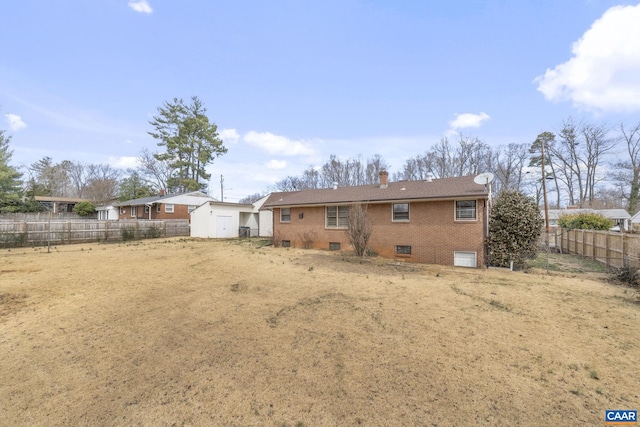 back of property featuring an outbuilding, a chimney, a storage unit, fence private yard, and brick siding