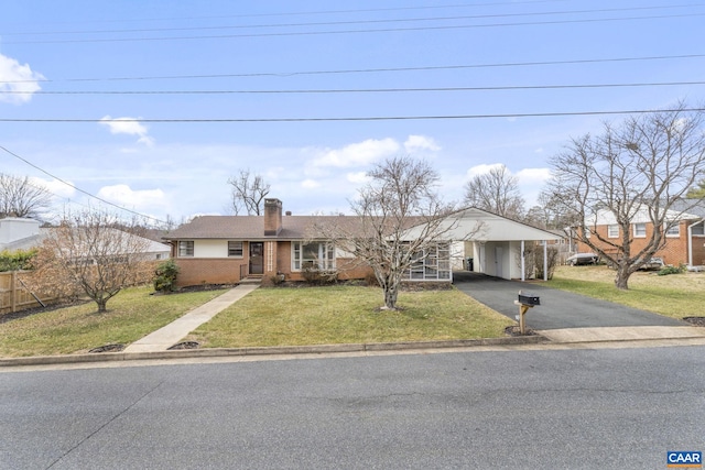 view of front of home with a front yard, fence, a carport, aphalt driveway, and brick siding