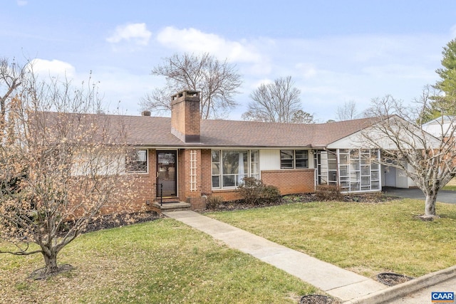 ranch-style house featuring brick siding, a shingled roof, a front lawn, a chimney, and driveway