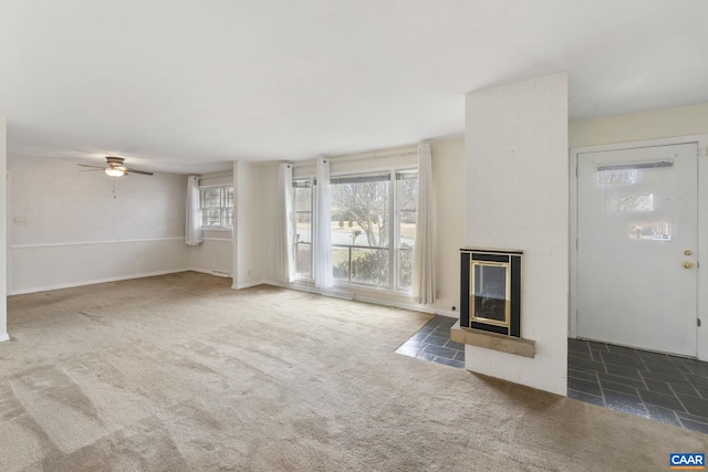 unfurnished living room with carpet flooring, ceiling fan, a fireplace, and baseboards