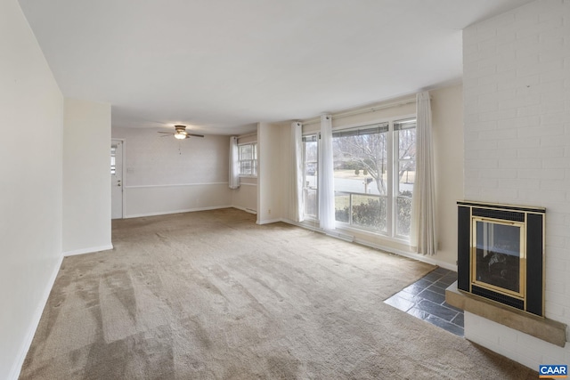 unfurnished living room with a wealth of natural light, baseboards, carpet floors, and a brick fireplace