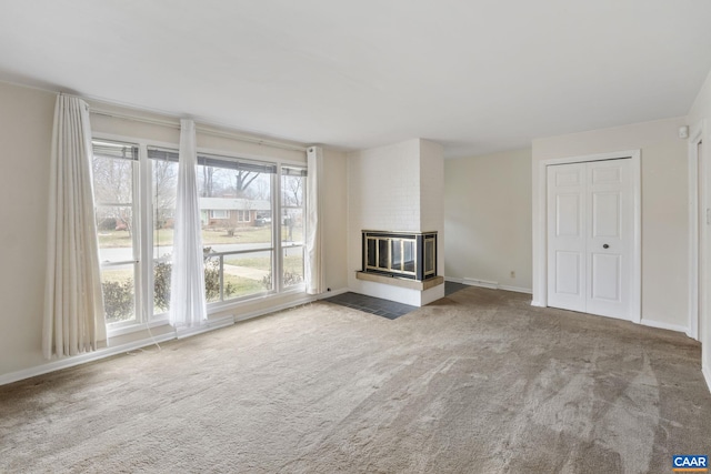 unfurnished living room with a multi sided fireplace, baseboards, and carpet floors