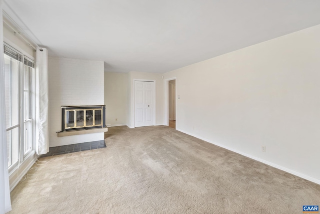 unfurnished living room featuring carpet flooring, baseboards, a healthy amount of sunlight, and a fireplace