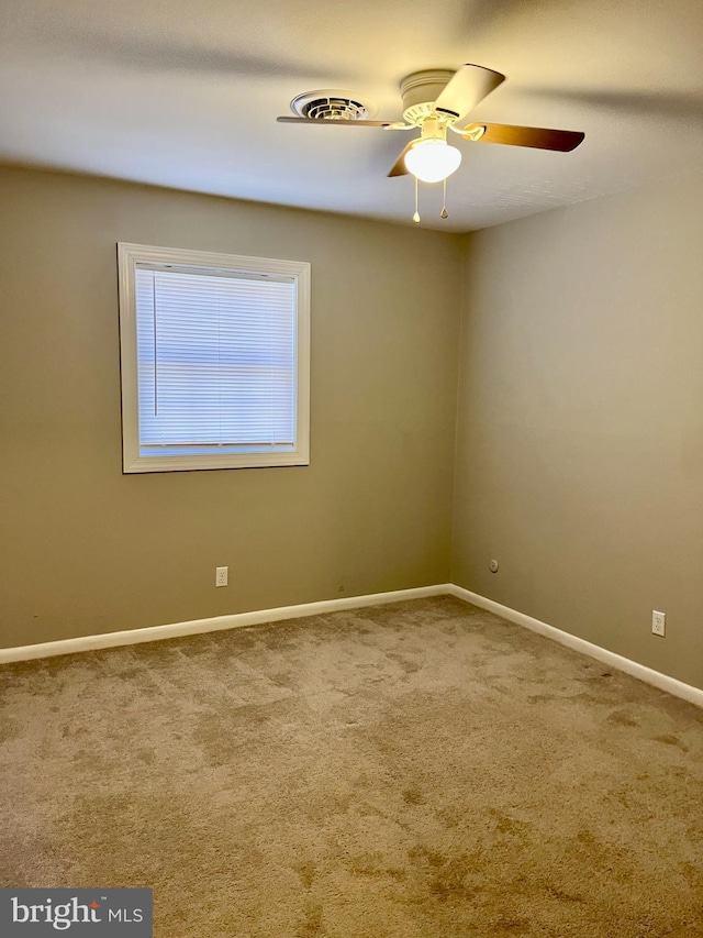 carpeted empty room featuring visible vents, baseboards, and a ceiling fan