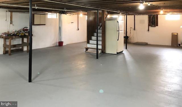 basement featuring stairs and freestanding refrigerator