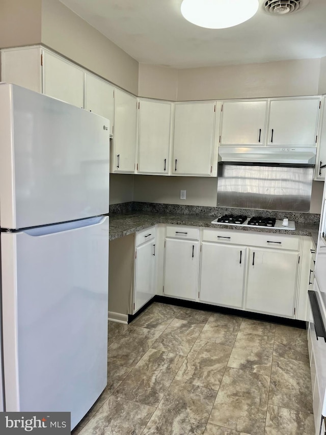 kitchen featuring white appliances, visible vents, under cabinet range hood, white cabinetry, and dark countertops