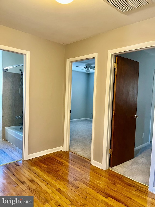 interior space with visible vents, connected bathroom, wood-type flooring, a closet, and baseboards