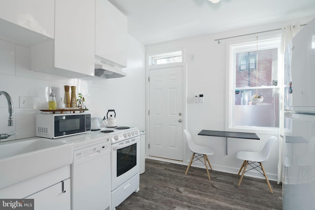 kitchen with under cabinet range hood, white appliances, white cabinets, decorative backsplash, and dark wood-style flooring