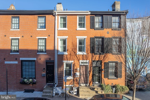 view of property featuring brick siding and a chimney