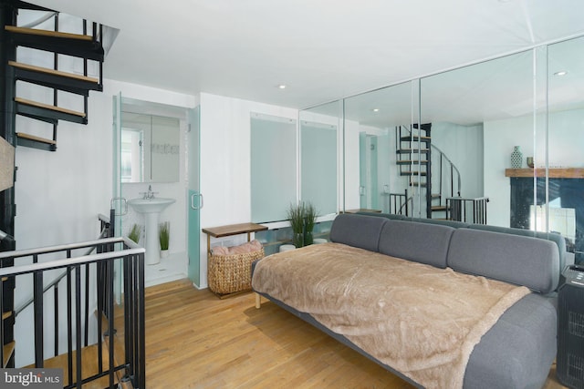 bedroom with a sink, recessed lighting, wood finished floors, and a fireplace