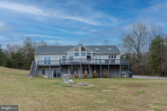 rear view of property featuring a yard, a fire pit, a wooden deck, and stairs