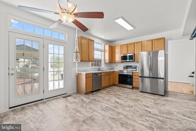 kitchen with baseboards, ceiling fan, light countertops, appliances with stainless steel finishes, and a sink