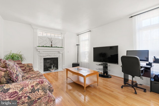 living room with hardwood / wood-style flooring, baseboards, and a high end fireplace