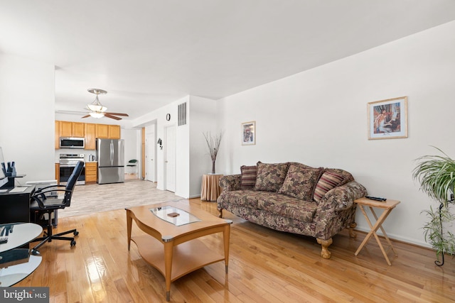 living room featuring baseboards, visible vents, light wood finished floors, and ceiling fan