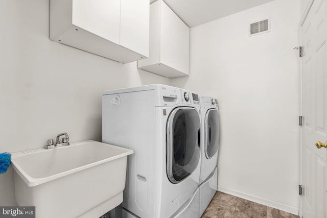 clothes washing area with visible vents, a sink, cabinet space, separate washer and dryer, and baseboards