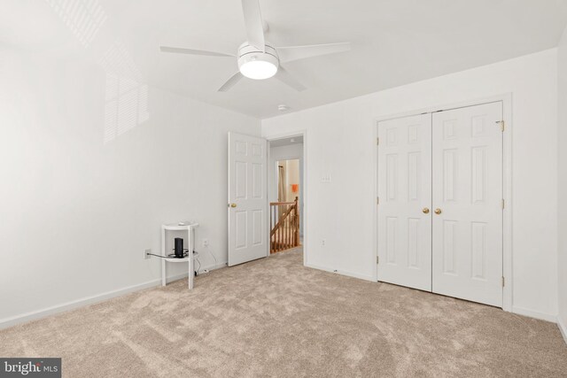 unfurnished bedroom with a closet, carpet flooring, ceiling fan, and baseboards