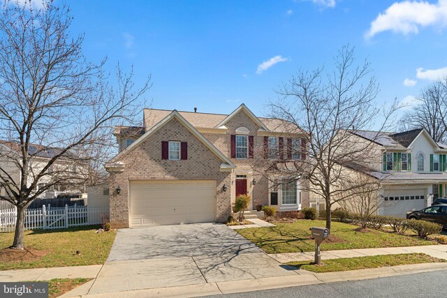 traditional home with brick siding, an attached garage, fence, a front yard, and driveway