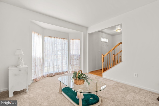 carpeted foyer with stairs and baseboards