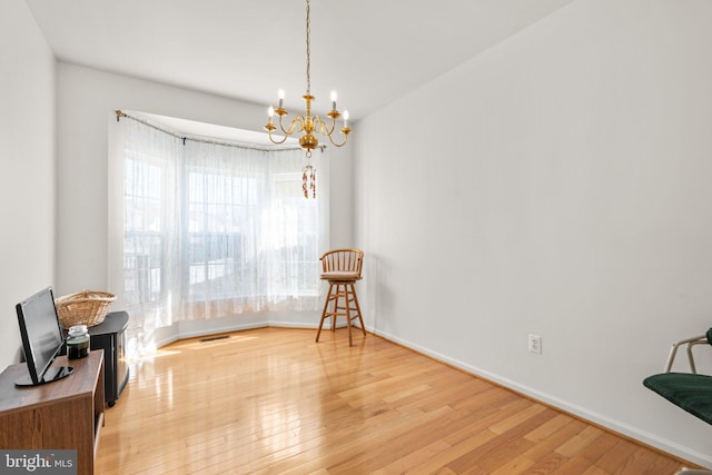 living area with light wood finished floors, a chandelier, and baseboards