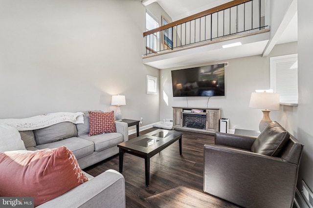 living area with a towering ceiling, baseboards, and wood finished floors