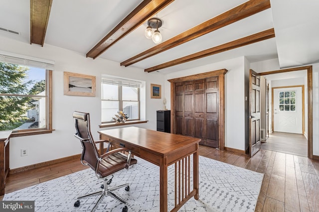 office space featuring a wealth of natural light, visible vents, baseboards, and wood-type flooring