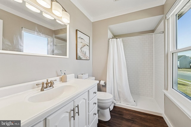 bathroom with tiled shower, toilet, vanity, and wood finished floors