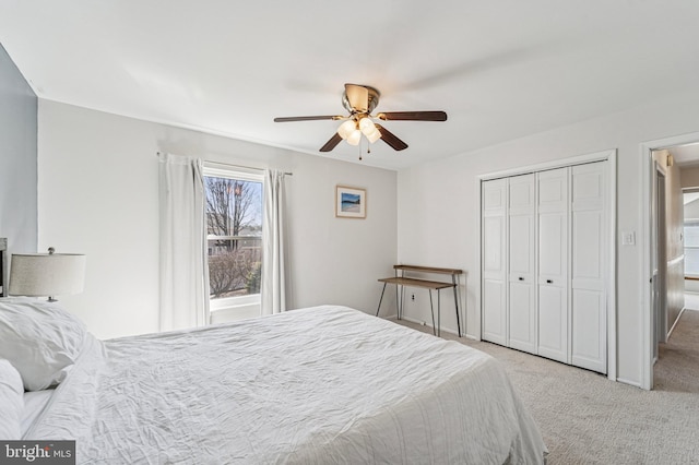 carpeted bedroom featuring a ceiling fan, a closet, and baseboards