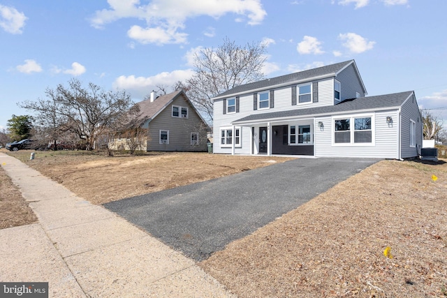 view of front facade with driveway, central AC, and roof with shingles