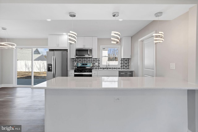 kitchen with light stone countertops, a sink, appliances with stainless steel finishes, white cabinetry, and tasteful backsplash