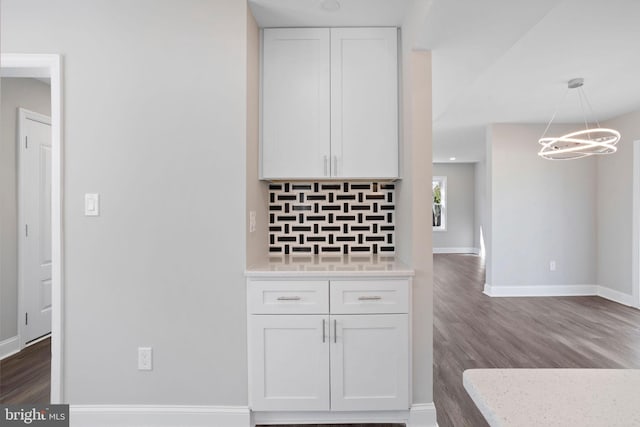 kitchen featuring decorative backsplash, white cabinetry, dark wood-type flooring, and baseboards