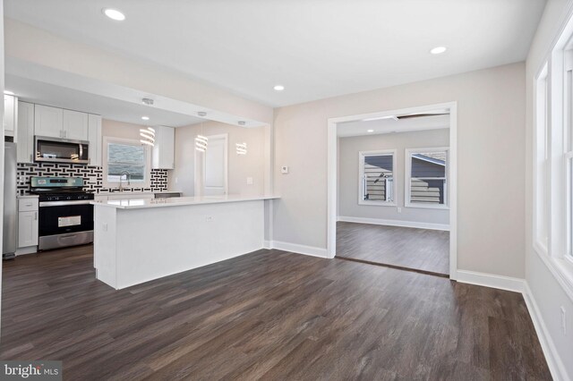 kitchen featuring dark wood-style floors, white cabinets, appliances with stainless steel finishes, and a peninsula