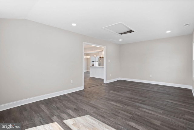 empty room with baseboards, dark wood finished floors, attic access, vaulted ceiling, and recessed lighting