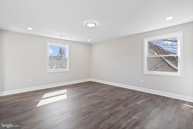 empty room featuring dark wood finished floors, visible vents, recessed lighting, and baseboards