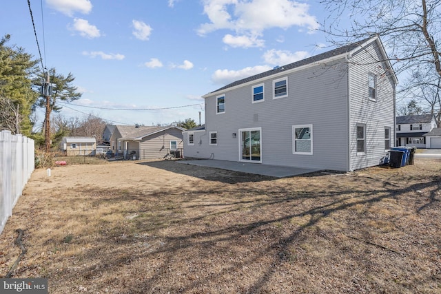 rear view of house featuring a patio, fence, and a lawn