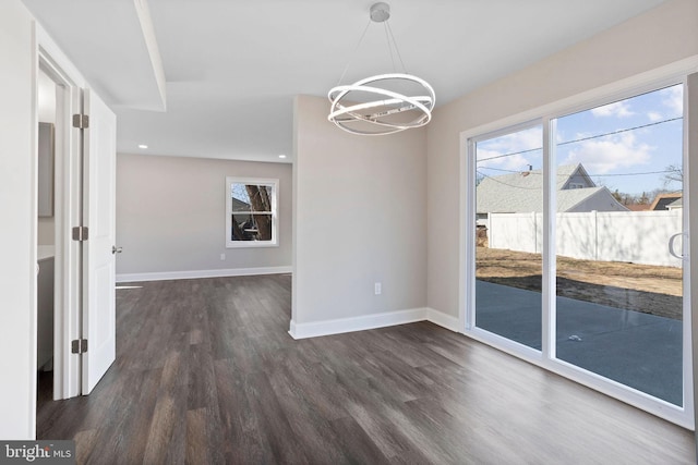 unfurnished dining area featuring recessed lighting, baseboards, an inviting chandelier, and dark wood-style flooring