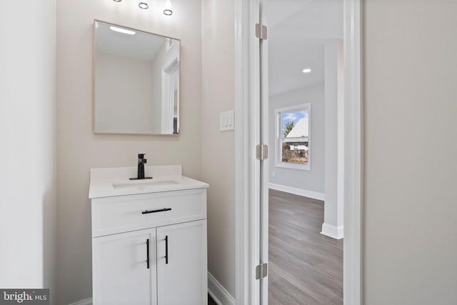 bathroom with baseboards, wood finished floors, and vanity