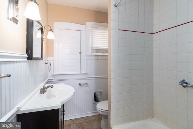 bathroom with a wainscoted wall, toilet, vanity, and visible vents