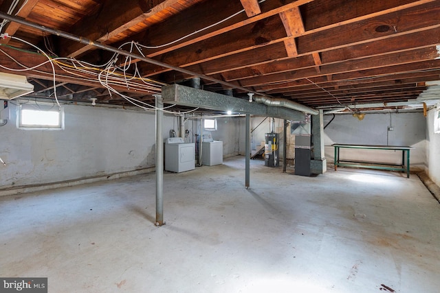 basement featuring washing machine and clothes dryer, heating unit, and gas water heater