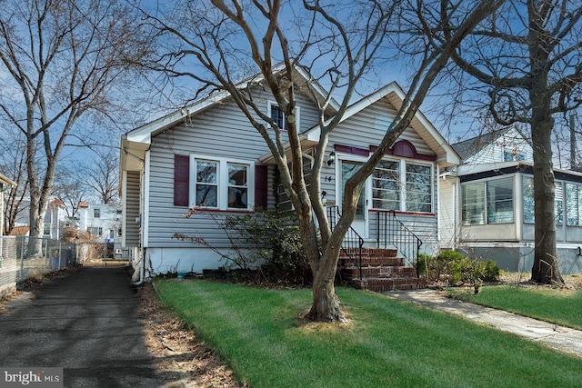 bungalow with a front yard and fence