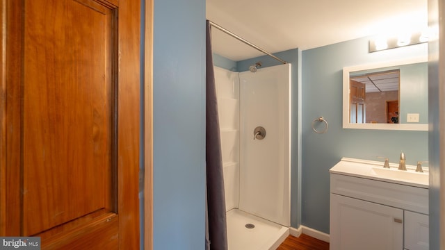 full bathroom featuring baseboards, a stall shower, and vanity