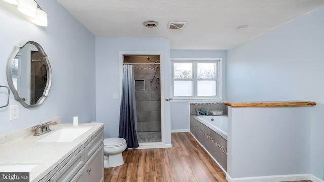 full bath with toilet, a tile shower, wood finished floors, a bath, and a sink