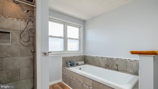 bathroom featuring a garden tub, wood finished floors, and tiled shower