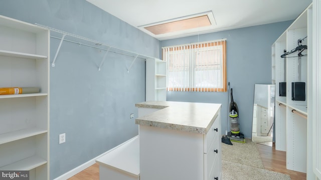 spacious closet with attic access and light wood-type flooring