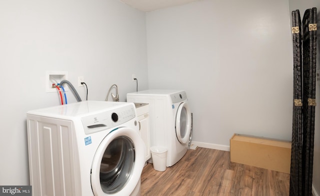 laundry area featuring laundry area, separate washer and dryer, light wood-style floors, and baseboards