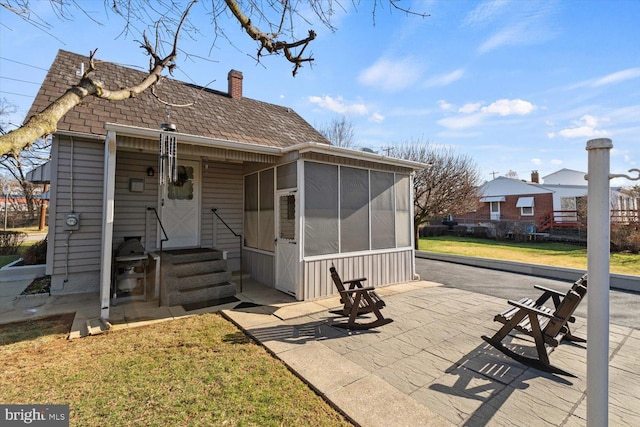 802 E 11th Ave, York, PA 17402 - view of front of home featuring a patio, a sunroom, a chimney, entry steps, and a front lawn