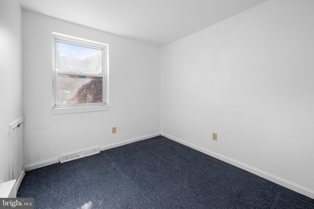 spare room with baseboards, visible vents, and dark colored carpet