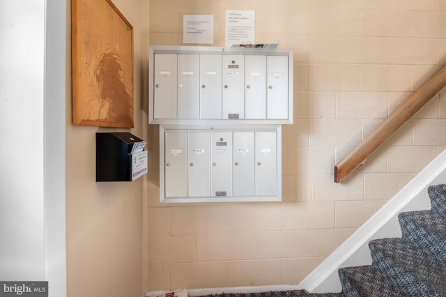 stairs featuring mail area and concrete block wall