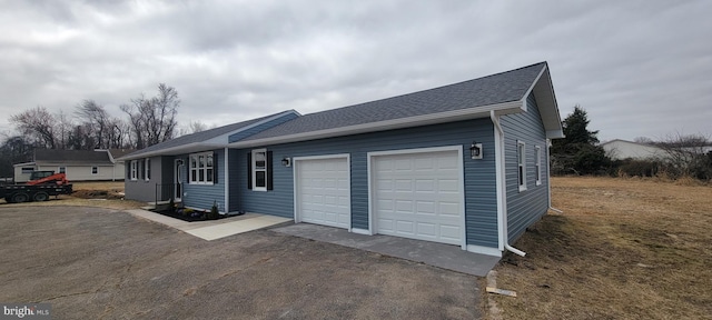 view of front of home featuring aphalt driveway, an attached garage, and a shingled roof