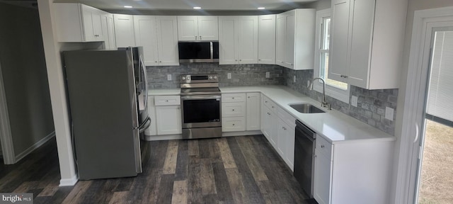 kitchen featuring light countertops, appliances with stainless steel finishes, dark wood-style floors, white cabinetry, and a sink