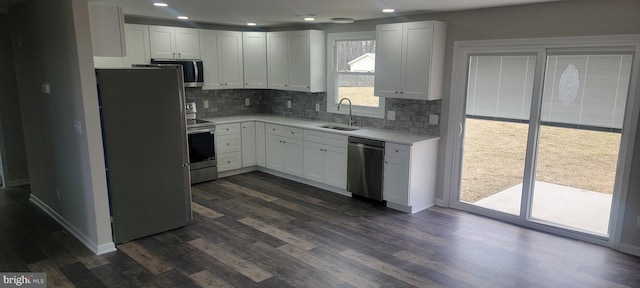 kitchen featuring a sink, light countertops, decorative backsplash, stainless steel appliances, and dark wood-style flooring